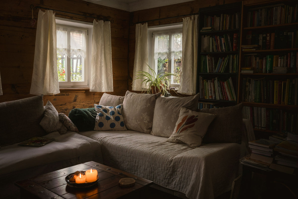 Candlelit cabin living room with a linen sofa and bookshelves